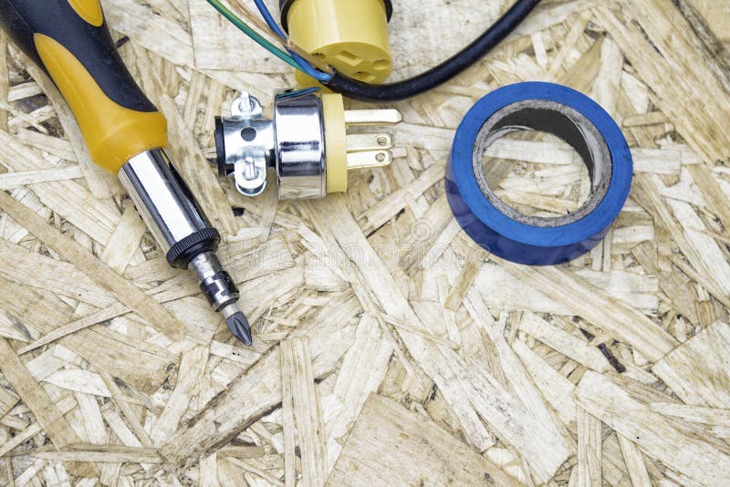 Screwdriver with wires, electrical tape and sockets on the background of OSB panel. The concept of repair. Screwdriver with wires, electrical tape and sockets royalty free stock photo